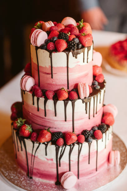 Big white and pink cake decorated with red strawberry and black berry